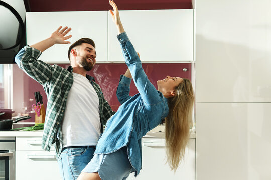 Couple dancing on the kitchen while cooking during sunny morning