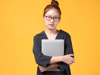 Portrait of happy casual Asian girl student with laptop isolated on yellow background. Back to school and learning concept.