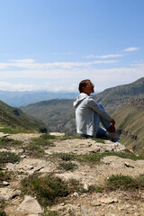 Naklejka premium woman person sitting on the edge of the canyon with beautiful mountains on background