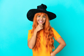 Young woman disguised as witch isolated on blue background with glasses and smiling