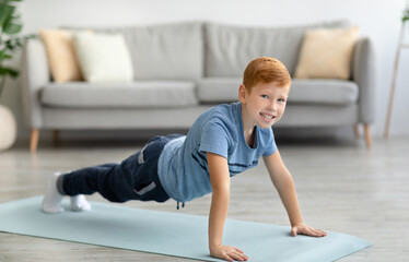Active kid exercising alone at home, doing push-up
