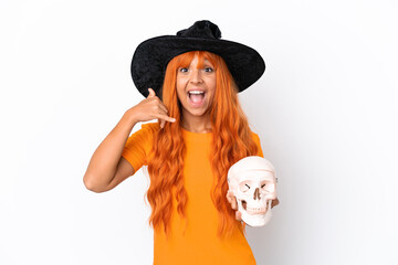 Young mixed race woman disguised as witch holding a skull isolated on white background making phone gesture. Call me back sign