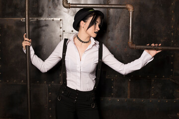Girl with suspenders and hat at the steel background and pipes