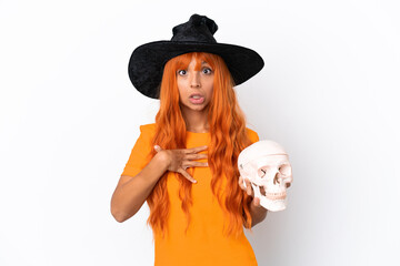 Young mixed race woman disguised as witch holding a skull isolated on white background surprised and shocked while looking right