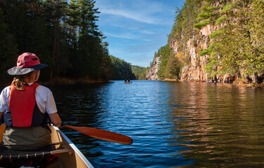 A canoe trip down the Barron River, through the Gorge  in Algonquin Park.  A female paddler looks towards another canoe and the start of the Gorge.  