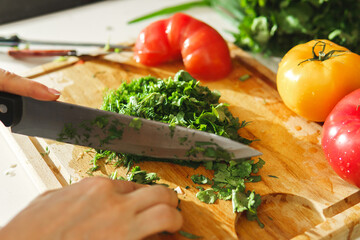 Obraz na płótnie Canvas Woman chopping parsley and dill for healthy vegetarian salad
