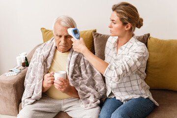 Woman taking care of her elderly grandfather with a cold syptoms