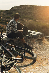Bike rider relaxing after downhill race on bicycle in a mountains