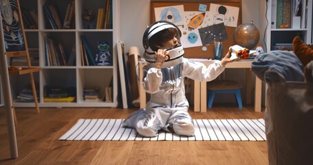 Childhood dreams about future. Happy little boy in astronaut suit playing space ship pilot, flying...