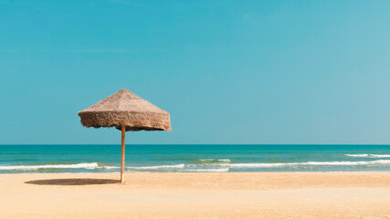 Sunny beach in seaside, straw parasol