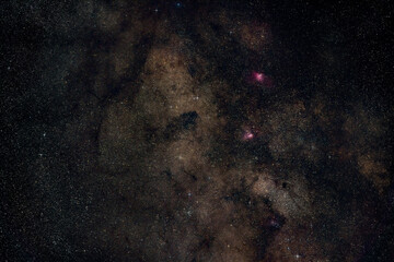 Night summer sky with milky way near Scutum constellation, bright Sagittarius clouds, purple Eagle and Swan nebula visible. Long exposure stacked photo