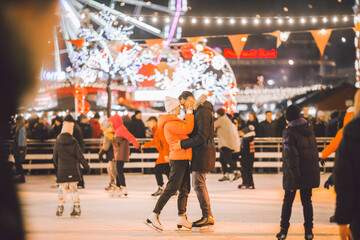couple hugging in Saint Valentine's Day. Young romantic pair having fun outdoors in winter. St. Valentines Day at city ice rink. New Year holidays. active date ice skating on ice arena on Christmas