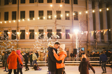 Beautiful Couple Ice Skating In City Centre. Young couple skating at a public ice skating rink outdoors. Theme ice skating rink and loving couple. Amazing winter holiday. Saint Valentine's Day