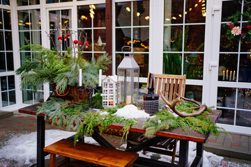 table decorated for new year with coniferous branches, lanterns and candles.