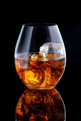 glass of whiskey with ice on black background