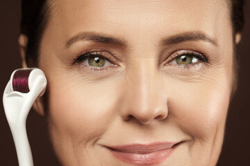 Middle aged woman using mesoroller for her facial skin.