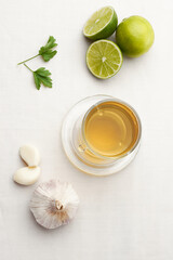 Infusion or tea of lemon and garlic, in a glass and placed on a white tablecloth