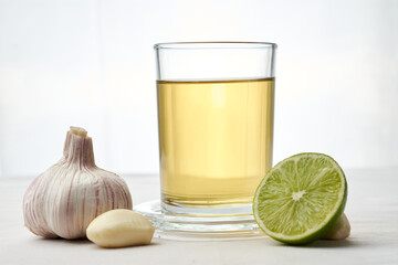 Infusion or tea of lemon and garlic, in a glass and placed on a white tablecloth