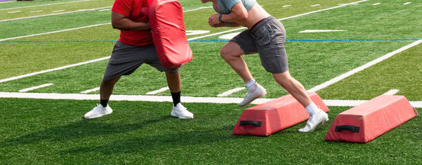 Football player avoiding barriers and hitting the coaches pad at the end during summer training camp