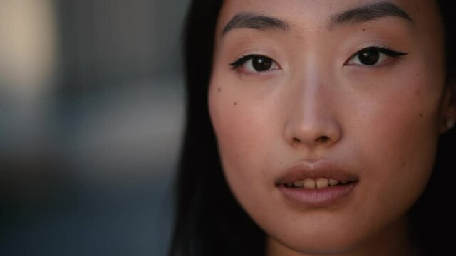 Portrait of young beautiful asian woman walking down and looking at the camera at the sunset. Close up of happy young girl smiling. High quality 4k footage