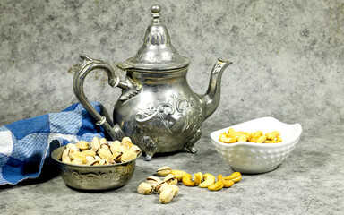 Arabic tea in silver teapot with tasty cashew nuts and pistachio