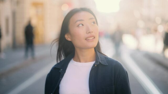 Portrait of young beautiful asian woman walking down at the sunset. Close up of happy young girl smiling. High quality 4k footage