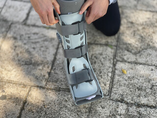 Person adjusting the air of the orthopedic boot used in rehabilitation for foot injury, fracture or ankle sprain.