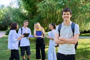 Portrait of male student in park campus, group of teenagers with teacher background
