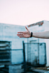 A strong man's hand with a black bracelet on the background of an abandoned building
