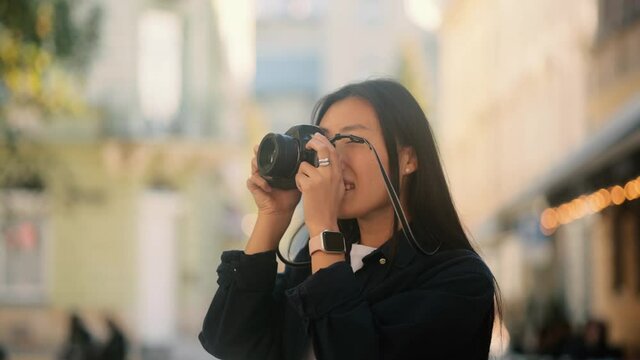 Asian hipster girl tourist in casual outfit photographing buildings architecture using camera. Time to travel. High quality 4k footage