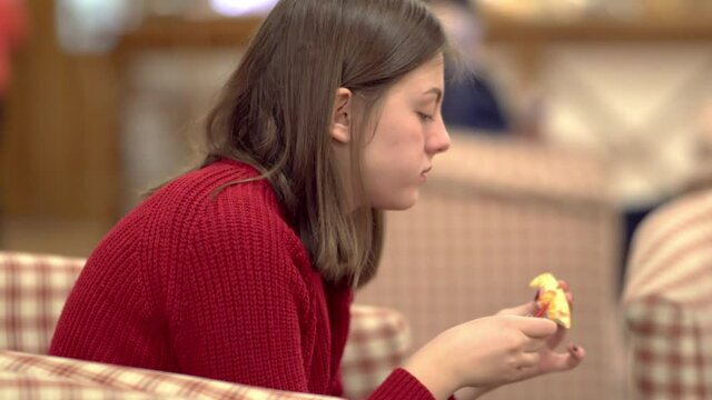 Girl in red sweater eating pizza at restaurant