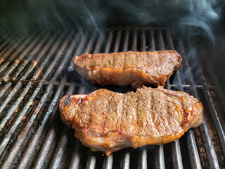Beef sirloin steaks cooking on a barbeque grill