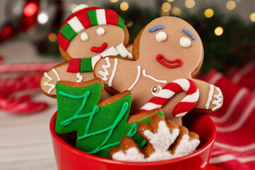 Delicious Christmas cookies in cup against blurred lights, closeup