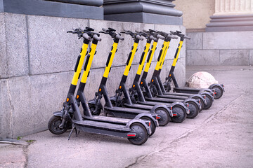 Electric scooters in row on the parking lot. Rental system on the city streets. Modern electric scooter parking. Alternative transportation, renewable energy.