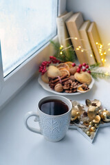 Tea Cup, cookies, christmas decor on windowsill. Christmas and New Year Holiday concept. festive winter season. home hygge atmosphere