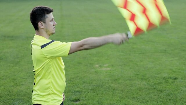 Assistant referee moving along the sideline during a soccer match. Linesman hand with flag signalling for offside trap to referee during football match