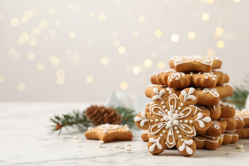Tasty Christmas cookies on white marble table against blurred festive lights, space for text
