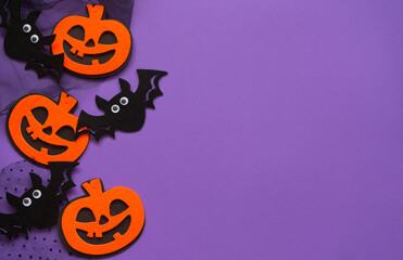 Halloween pumpkin and bat figurines on purple background