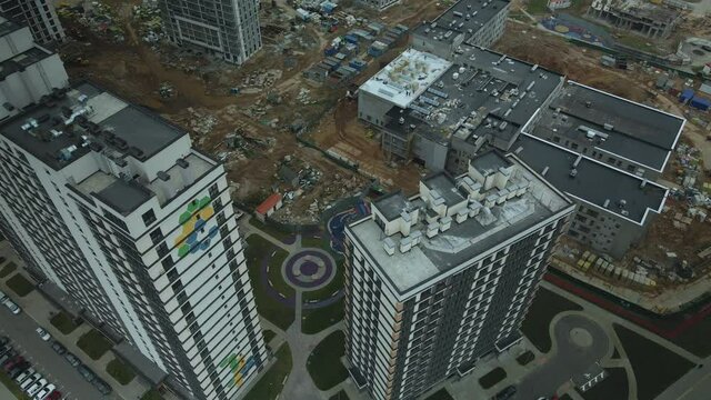 Construction of modern multi-storey buildings. Construction of a new city block. Buildings under construction and tower cranes. Aerial photography in cloudy weather.
