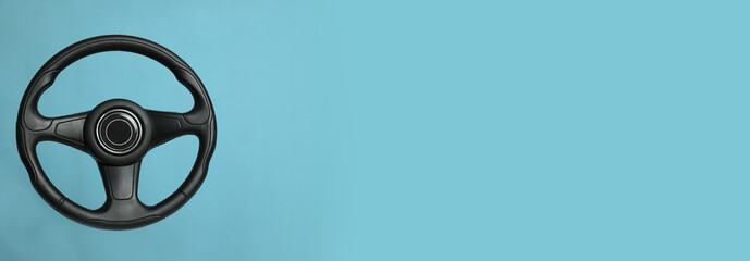 Black steering wheel on light blue background, top view with space for text. Banner design - Powered by Adobe