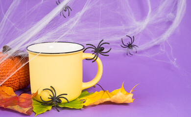 Halloween composition. Yellow cup, cobwebs and spiders around