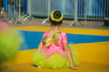 A girl in a butterfly dance costume sits in anticipation of a performance