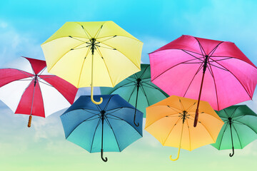 Fototapeta na wymiar Group of different colorful umbrellas against blue sky on sunny day