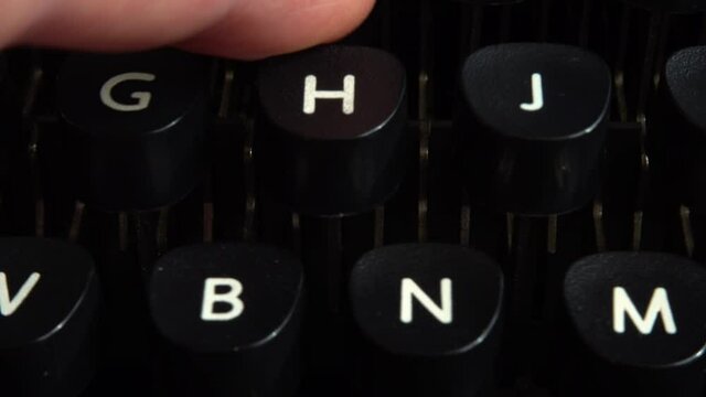 A man presses his fingers on the keys of a vintage typewriter.