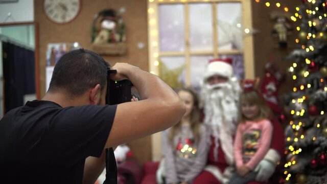 Photographer make a photo session of young children with Santa Claus during Christmas, New Year holidays
