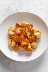 fried potatoes with chanterelles mushrooms on a white plate on a white background for dinner