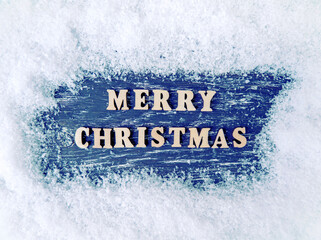 Christmas wooden background with snow and snowflake. The inscription Merry Christmas