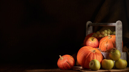 Ripe pumpkins, apples and pears in wooden box on dark background with copy space. Thanksgiving background. Autumn harvest