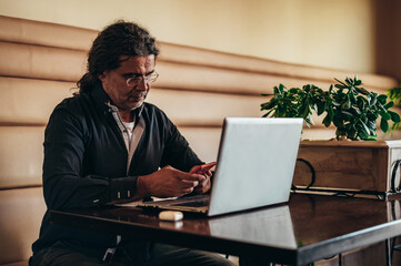 Senior hispanic cuban men using a laptop while working in the cafe