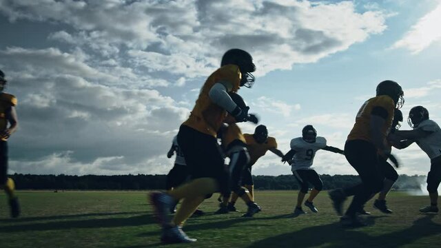 American Football Field Two Teams Compete: Players Pass and Run Attacking to Score Touchdown Points. Athletes Brutally Compete for the Ball, Tackle Each other. Cinematic Slow Motion with Dramatic Shot